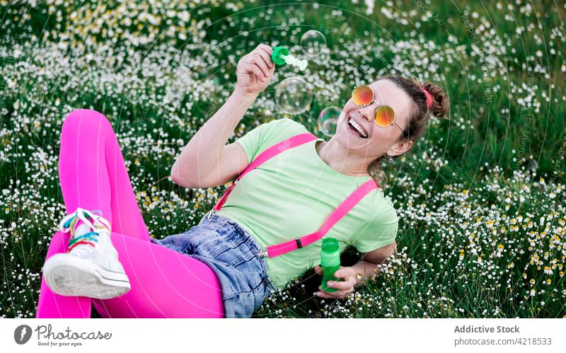 Aufgeregte Frau spielt mit Seifenblasen auf einer üppigen Wiese Freude spielen Tal sorgenfrei aufgeregt Natur Outfit expressiv Spaß hell Glück heiter froh