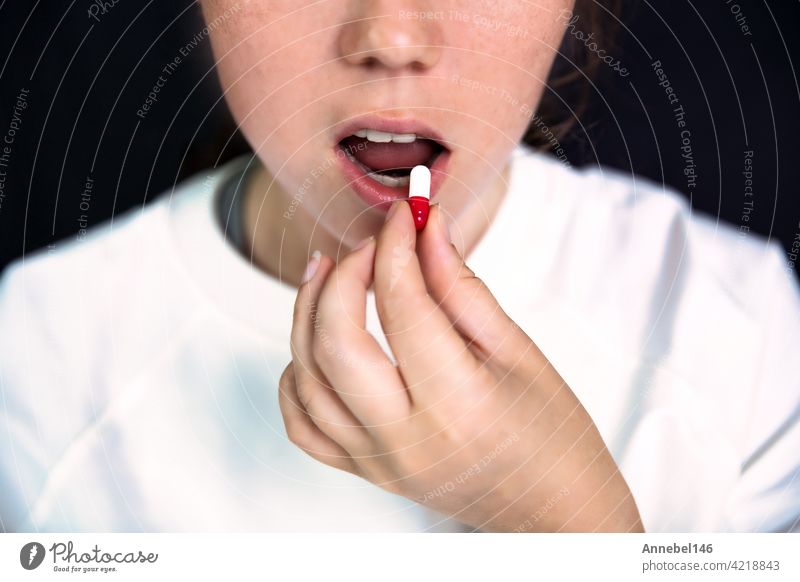 Junge Frau, Teenager mit Kapsel auf Zange auf dunklen schwarzen Hintergrund, Pillen nehmen. Medizin, Drogen, Gesundheit Konzept medizinisch Design Medikamente