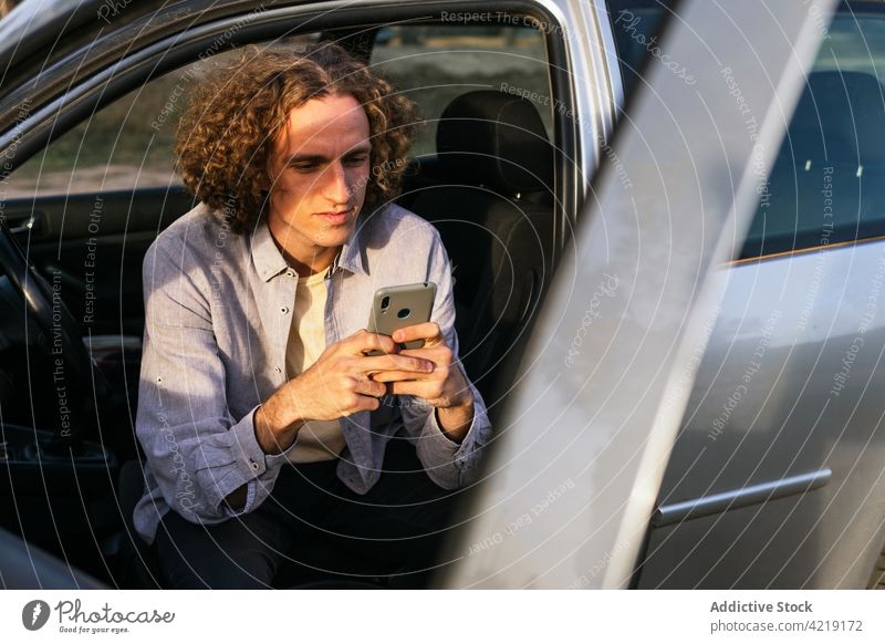 Mann sitzt im Auto und benutzt ein Mobiltelefon PKW Smartphone benutzend Fahrer Telefon Verkehr Kommunizieren Fahrzeug Apparatur männlich Gerät Browsen Ausflug