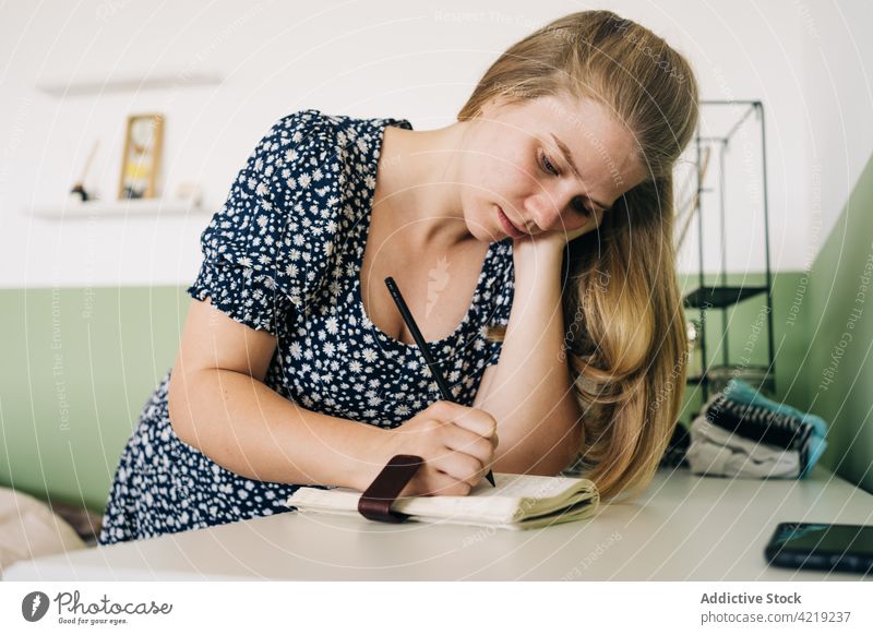 Frau schreibt in Notizbuch am Tisch im Haus zur Kenntnis nehmen Notebook sich auf die Hand lehnen achtsam feminin sanft Porträt Schreibstift schreiben Papier