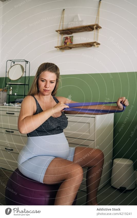 Schwangere Frau auf Yogaball, die mit Gummiband trainiert Widerstandsband Übung schwanger Training Ball Sport mütterlich heimwärts üben elastisch Fitness Bauch