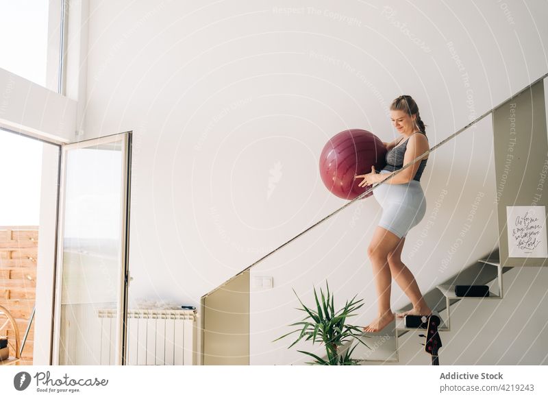 Schwangere Frau mit Gymnastikball auf der Treppe zu Hause Yoga Ball schwanger Spaziergang mütterlich Lächeln warten heimwärts Übung Sport Fitness Bauch