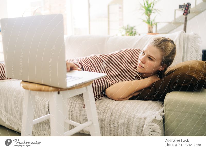 Müde Frau, die sich auf dem Sofa ausruht und einen Film auf dem Laptop ansieht zuschauend Wochenende freie Zeit müde ruhen benutzend Apparatur Gerät heimwärts