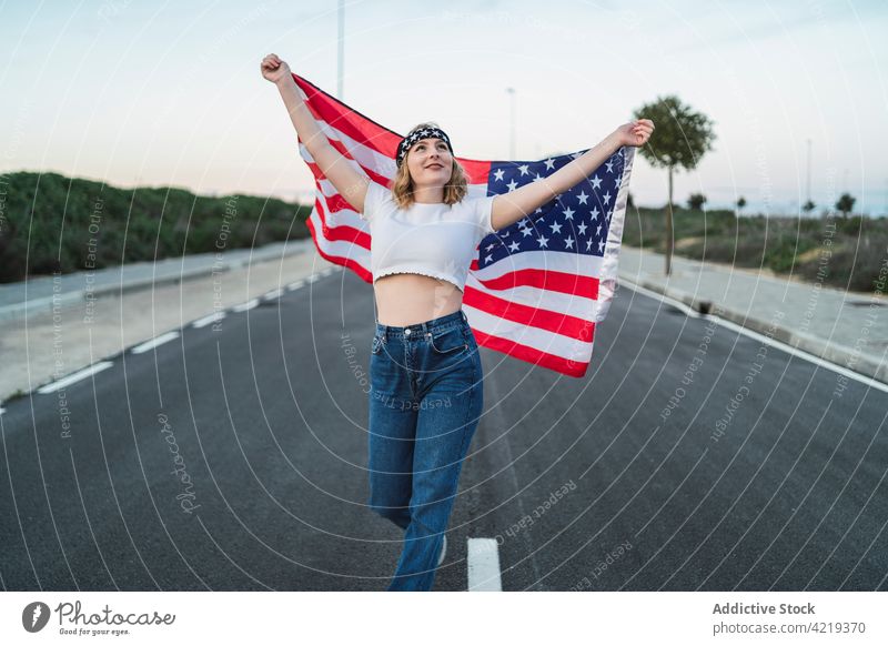 Zufriedene Frau mit USA-Flagge auf der Straße stehend Fahne Patriotin sorgenfrei Inhalt Freiheit national Sonnenuntergang Symbol Amerikaner amerika
