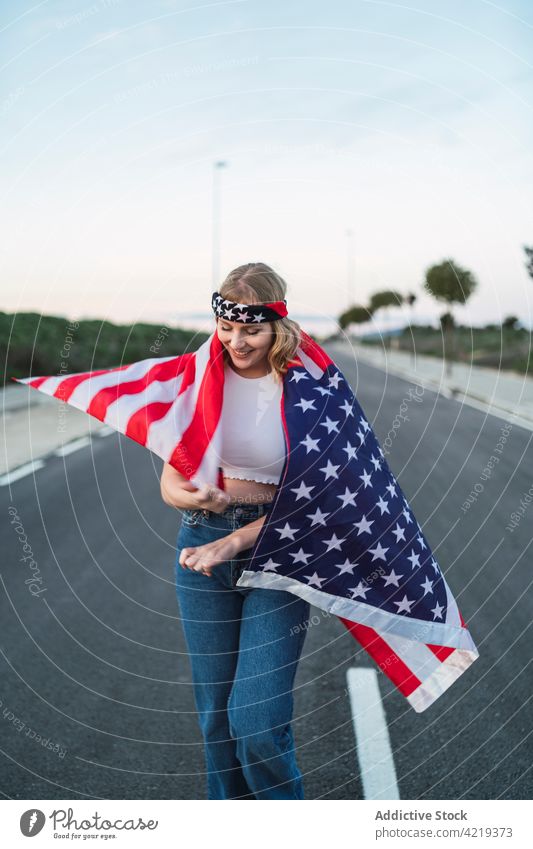 Zufriedene Frau mit USA-Flagge auf der Straße stehend Fahne Patriotin sorgenfrei Inhalt Freiheit national Sonnenuntergang Symbol Amerikaner eingewickelt amerika