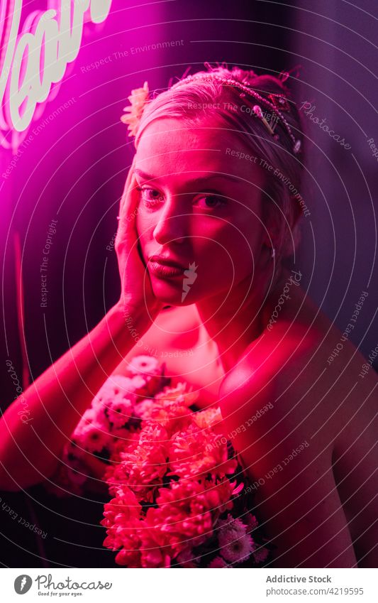 Stilvolle Frau mit Blumen im Studio mit Neonlicht Blumenstrauß neonfarbig Porträt Farbe elegant nackte Schultern geblümt hell farbenfroh Licht natürlich frisch