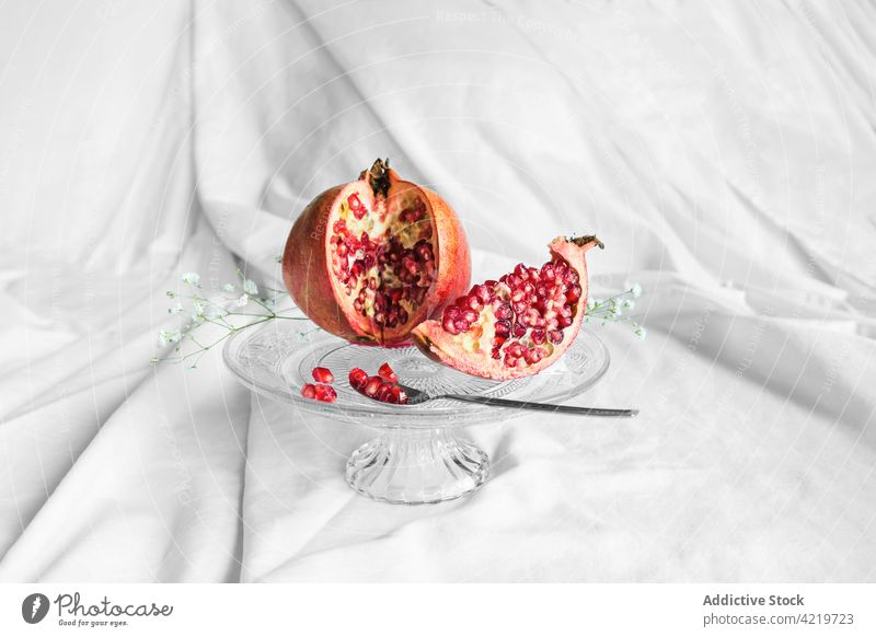 Lecker geschnittener Granatapfel auf Ständer mit Löffel Frucht Samen natürlich Vitamin frisch stehen Zweig Gewebe zerknittert Blume organisch lecker reif Aroma