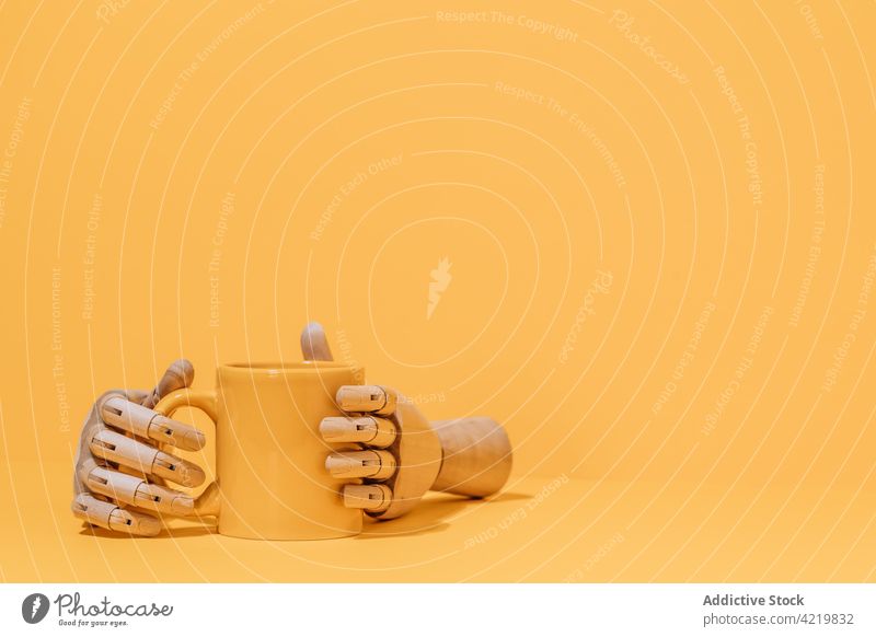 Hölzerne Hand mit Kaffeetasse auf gelbem Hintergrund hölzern Konzept Becher Atelier Design Getränk kreativ sehr wenige Tasse Objekt einfach Utensil Farbe Stil