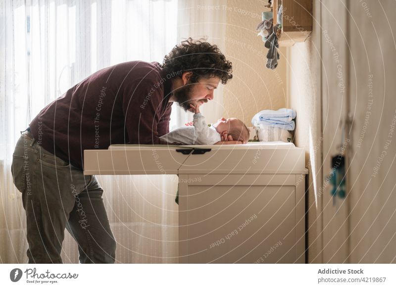 Vater im Umgang mit seinem neugeborenen Baby zu Hause interagieren Vaterschaft unschuldig Säuglingsalter nach vorne lehnen Tisch heimwärts Mann Zusammensein