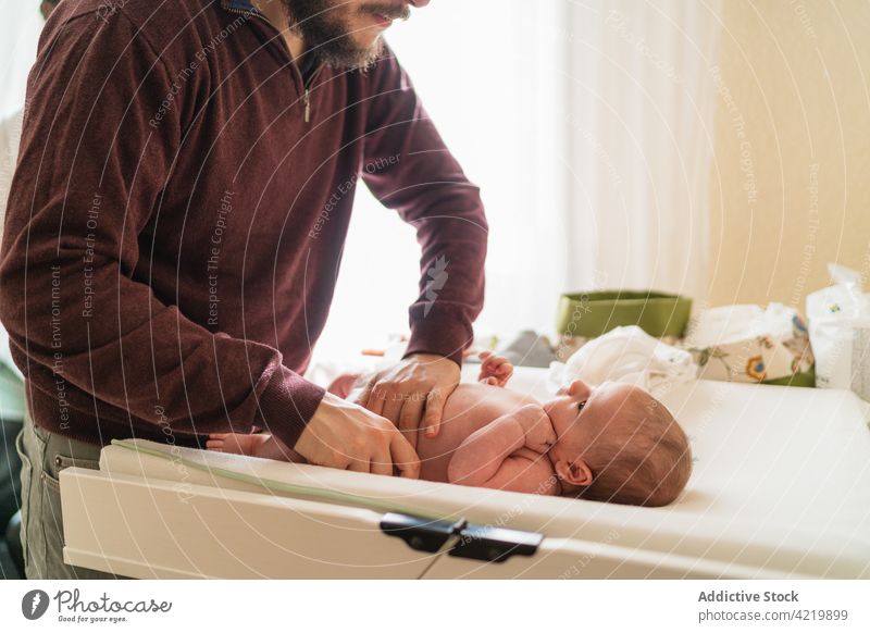 Der Vater wechselt die Windel des neugeborenen Babys zu Hause Mann angezogen Säugling Papa Vaterschaft heimisch süß Tisch heimwärts unrasiert