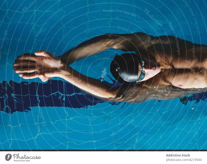Sportler mit Schwimmbrille schwimmt während des Trainings im Pool Schwimmer schwimmen Arme hochgezogen Übung üben Mann Motivation Energie Stärke maskulin