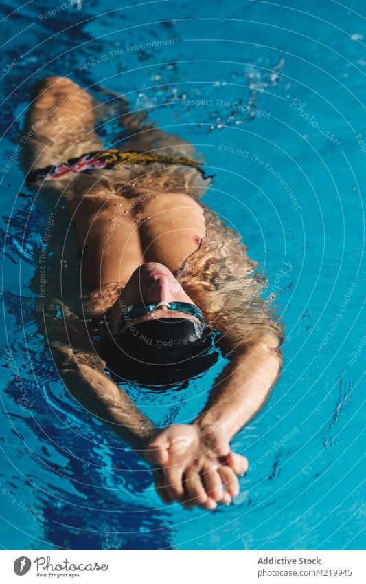 Sportler mit Schwimmbrille schwimmt während des Trainings im Pool Schwimmer schwimmen Arme hochgezogen Übung üben Mann Motivation Energie Stärke maskulin