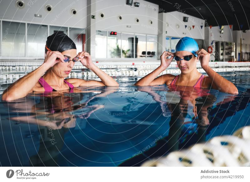 Schwimmer beim Anlegen der Schwimmbrille vor dem Training im Schwimmbad angezogen Schutzbrille Sport Wohlbefinden professionell Frauen Pool Wasser Badekappe