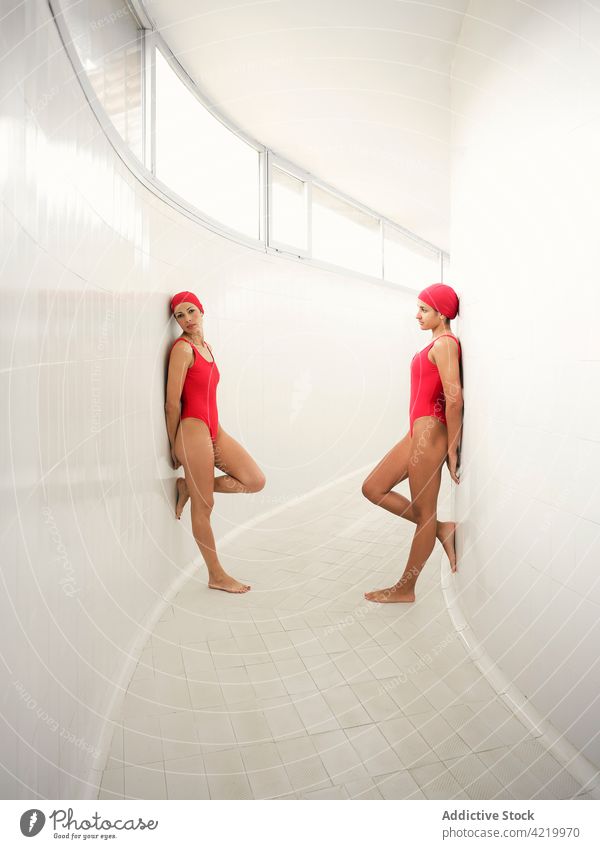 Schwimmer in Badeanzügen lehnen an Wänden im Korridor Athlet Badebekleidung Bein angehoben Sport Gang duo Körper Hand hinter dem Rücken professionell Frauen