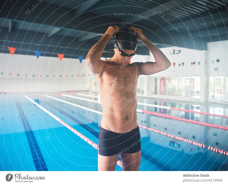 Schwimmer mit Schwimmbrille vor dem Training gegen den Pool setzen Sportler Schwimmsport vorbereiten Unterleib Körper maskulin Mann Badehose Athlet