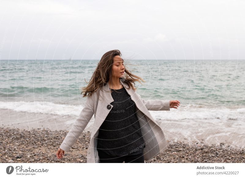 Unbekümmerte Frau, die sich am Meer umdreht sorgenfrei sich im Kreise drehen MEER verträumt Herbst Meeresufer Seeküste ruhig genießen Wind fliegendes Haar
