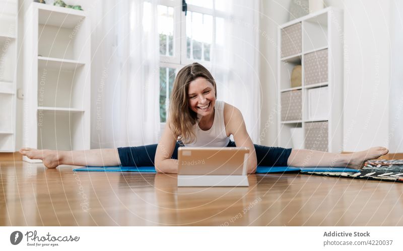 Fröhliche Frau in breiter Spagat-Pose sitzend und Yoga machend Split üben Video online Tutorial Lektion heimwärts beweglich Asana breite Spagat-Pose