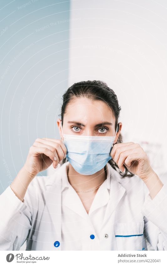Krankenschwester legt Einwegmaske in der Klinik an Krankenpfleger angezogen Mundschutz behüten Gesundheitswesen medizinisch Frau Porträt zeigen