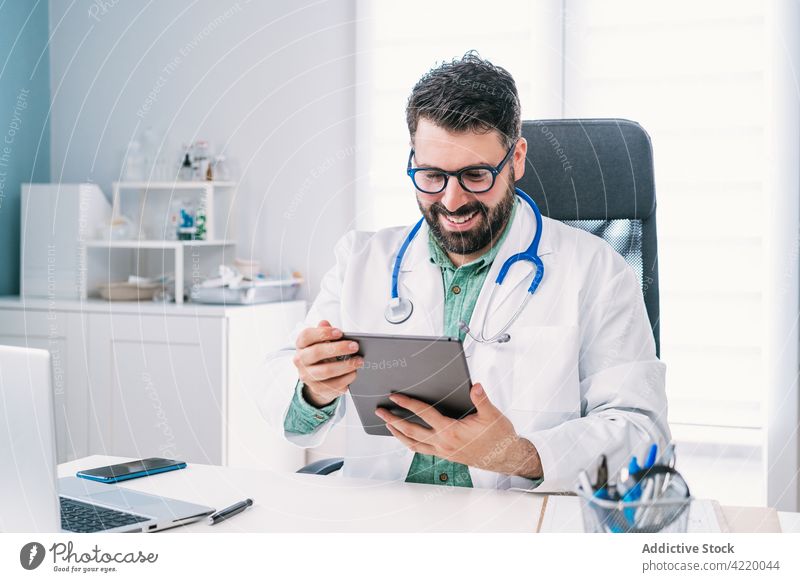 Lächelnder Arzt mit Tablet während eines Videogesprächs in der Klinik arzt Tablette Videoanruf reden Internet online Mann Krankenhaus benutzend Apparatur Gerät
