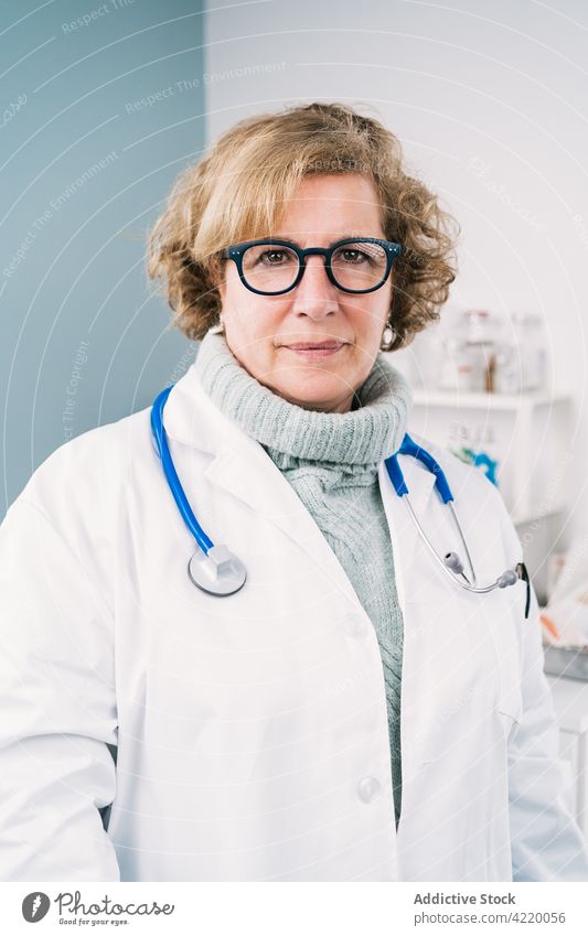 Älterer Arzt mit Stethoskop bei der Arbeit in der Klinik arzt selbstbewusst Uniform Beruf Spezialist Brille Frau Krankenhaus Porträt professionell Starrer Blick