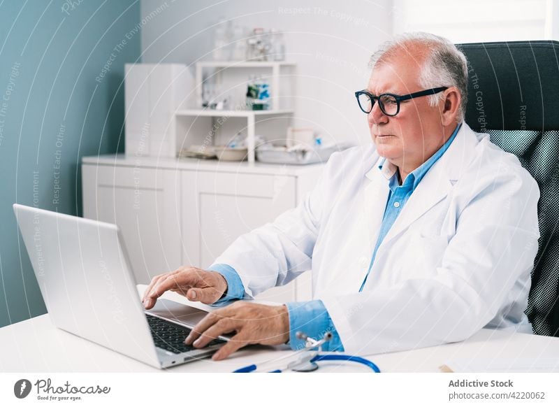 Oberarzt arbeitet am Laptop im Krankenhaus Arzt Tippen medizinisch professionell Job Uniform Mann benutzend Apparatur Gerät Arbeit Internet ernst online Surfen