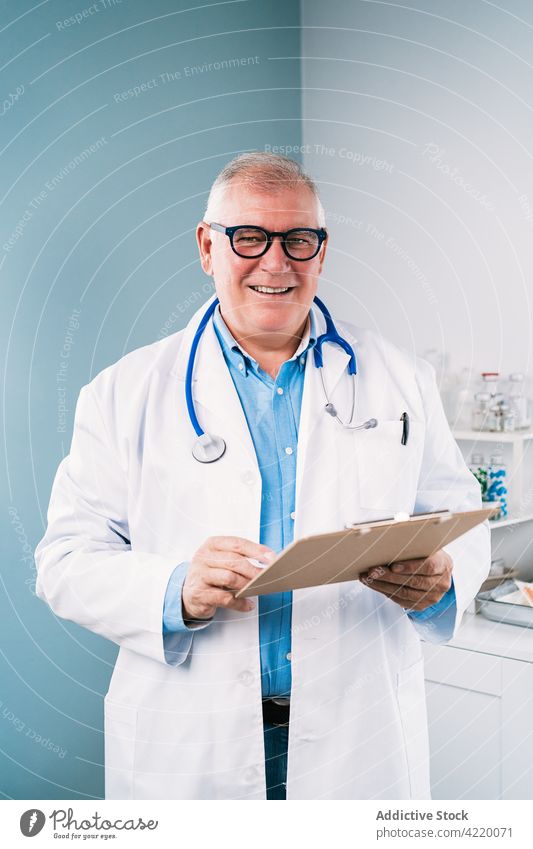 Arzt liest in der Klinik auf Papier arzt Uniform Lächeln Arbeit Beruf Glück Spezialist lesen medizinisch Mann Robe heiter Stethoskop Instrument schreiben