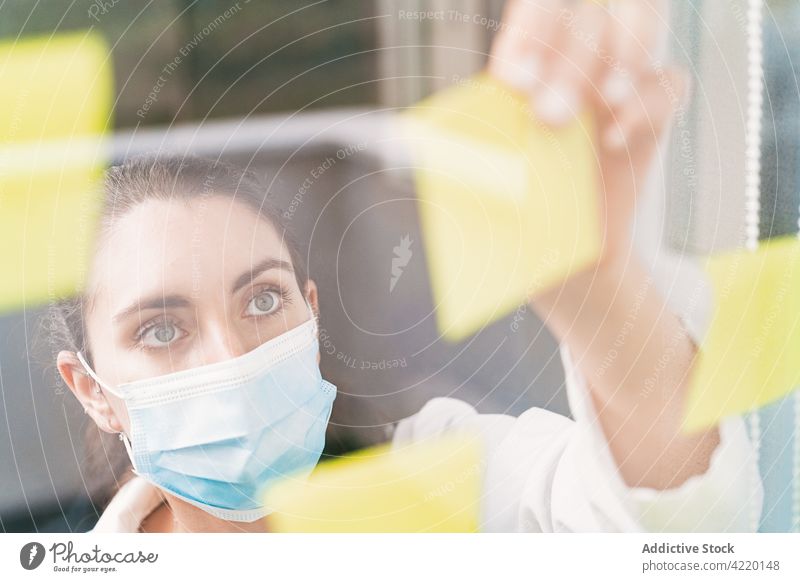Arzt klebt Papieraufkleber auf eine transparente Wand in einer Klinik Aufkleber Glaswand Strategie medizinisch professionell Frau Arbeit analysieren