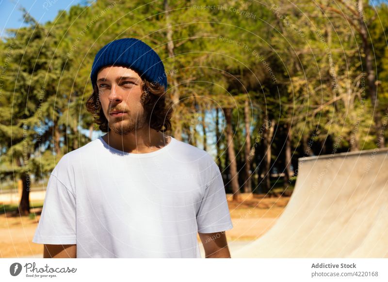 Porträt eines jungen Mannes mit Bart Beanie Hut Vollbart blau Kaukasier Schlittschuhlaufen Skateboard Skatepark T-Shirt Park Skateplatz Sport gutaussehend urban