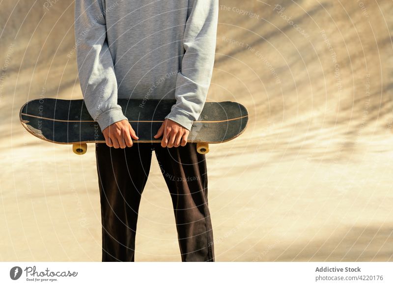 Ausschnitt eines Mannes, der sein Skateboard hält Holzplatte jung Schlittschuhlaufen unkenntlich Skatepark Porträt Lifestyle Menschen Asphalt Schatten Sommer