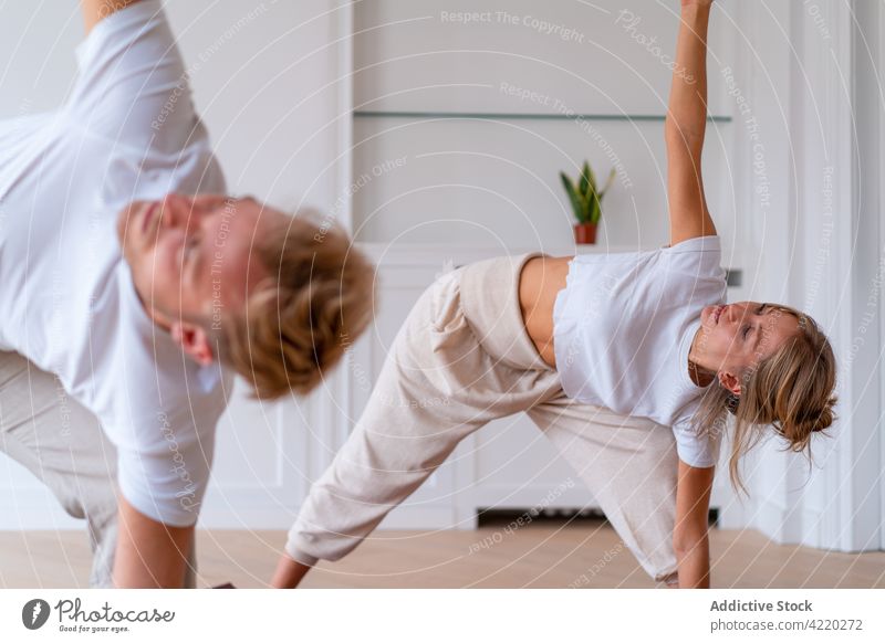 Paar übt Yoga in Dreieckspose zusammen zu Hause Morgen Zusammensein üben heimwärts Dehnung Triangel-Pose Namaste Asana sich[Akk] entspannen Partnerschaft