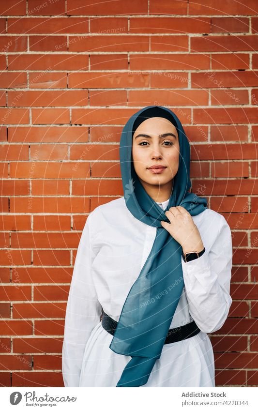 Ethnische Frau im Hidschab in der Stadt lehnt sich an eine Backsteinmauer Großstadt Hijab Straße ethnisch muslimisch Kopftuch Kopfbedeckung Stil Kopfschmuck