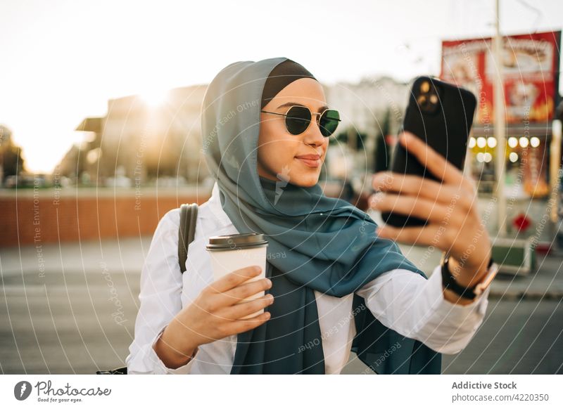 Muslimische Frau macht Selfie mit Smartphone unter soziale Netzwerke Mobile Telefon ethnisch muslimisch Kopftuch Straße Apparatur Kommunizieren benutzend Gerät