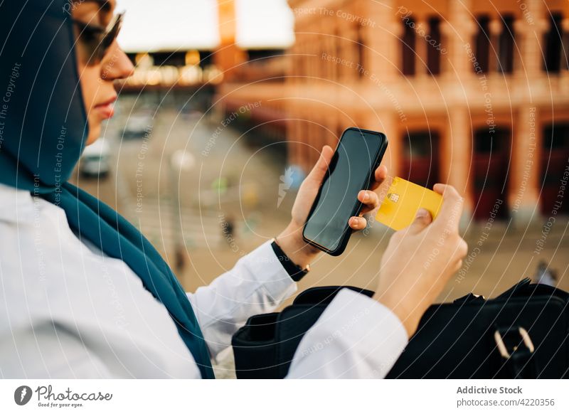 Crop Muslimische Frau beim Bezahlen mit Plastikkarte beim Online-Shopping Werkstatt online bezahlen Zahlung Kauf Smartphone benutzend Internet ethnisch
