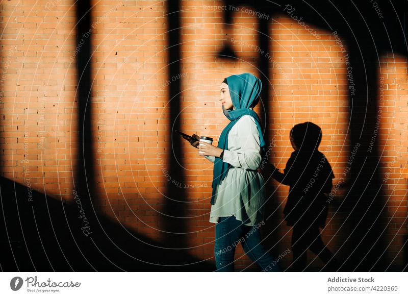 Muslimische Frau benutzt Smartphone im Bahnhof Browsen unterirdisch benutzend Imbissbude Großstadt trinken Surfen Hijab ethnisch muslimisch Mobile Internet