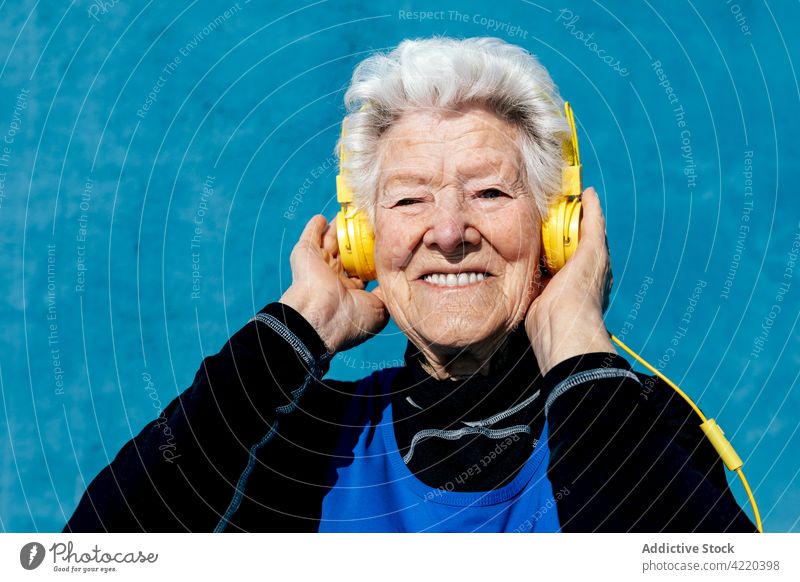Fröhliche ältere Frau, die im Studio Musik hört Senior zuhören Kopfhörer Gesang Lächeln genießen Klang gealtert graues Haar Großmutter Apparatur Gerät heiter