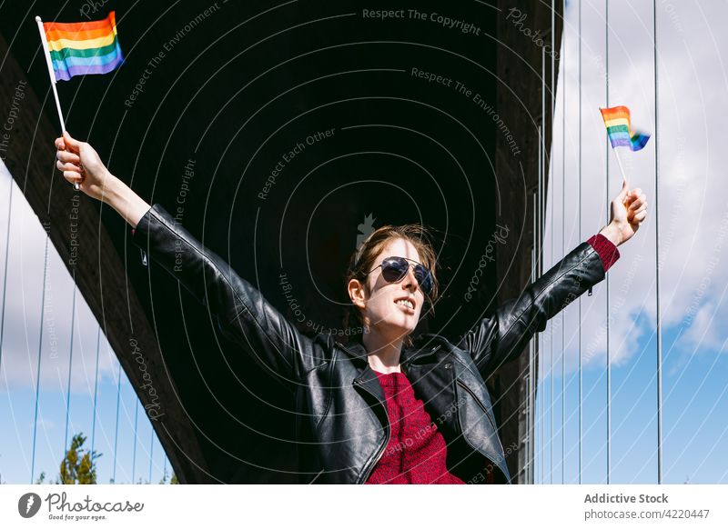 Sorglose Frau mit LBGT-Fahnen auf der Straße lgbt lesbisch Regenbogen lgbtq stolz Homosexualität Freiheit Stolz Großstadt Arme hochgezogen schwul urban rechts