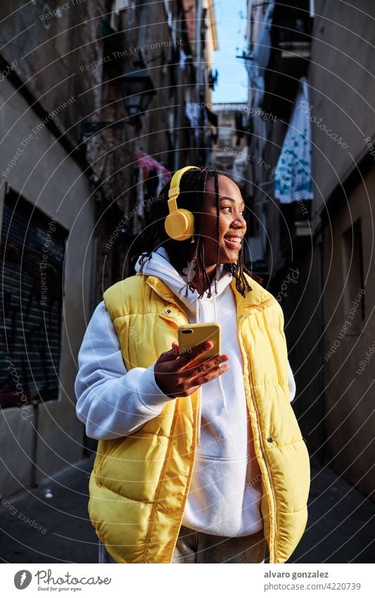 Frau hört Musik mit Kopfhörer und Telefon. che Mobile urban Gerät genießend Technik & Technologie im Freien Afrikanisch Amerikaner Drahtlos hören Smartphone