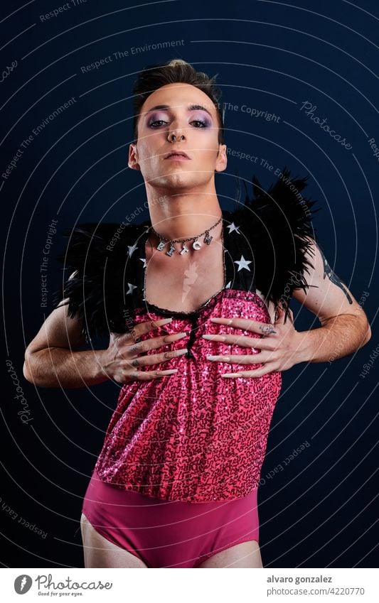 Junge Transgender-Modell mit rosa Kleid und dunkelblauem Hintergrund che Homosexualität Vielfalt feminin Porträt jung Typ Schminke männlich Person Kaukasier