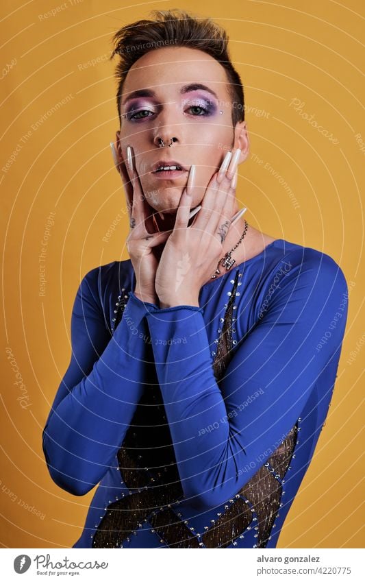 Junge Transgender-Modell mit gelben Hintergrund ein blaues Kleid che Homosexualität Vielfalt feminin Porträt jung Typ Schminke männlich Person Kaukasier