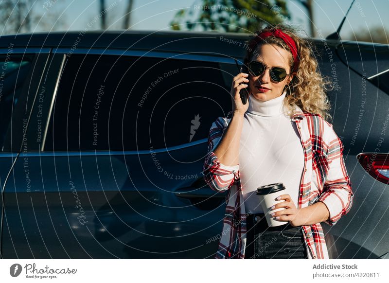 Stilvolle Frau, die in der Nähe eines Autos mit ihrem Smartphone spricht sprechen PKW Großstadt reden Imbissbude trinken Automobil Gespräch Anruf Apparatur