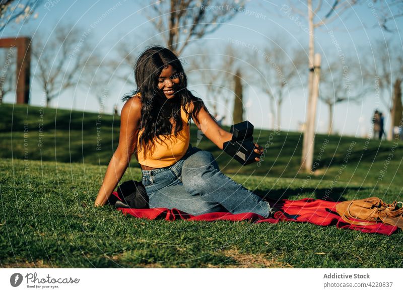Lächelnde schwarze Frau macht Selfie mit Sofortbildkamera im Garten sofort Fotokamera Selbstportrait retro Park Gedächtnis altehrwürdig Afroamerikaner ethnisch