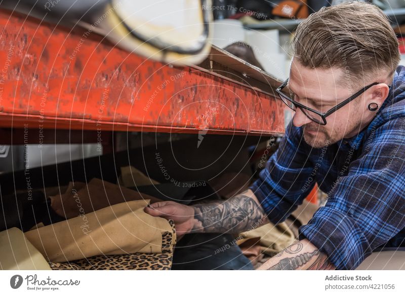 Handwerker bei der Arbeit mit verschiedenen Stoffen in der Werkstatt Kunsthandwerker Gewebe Hipster wählen Polsterung pflücken kreativ Material Mann männlich