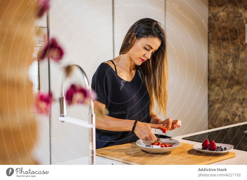 Konzentrierte Frau schneidet in der Küche frische Erdbeeren für das Frühstück geschnitten kulinarisch Rezept Vitamin gesunde Ernährung lecker vorbereiten