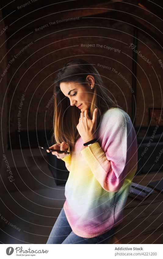 Konzentrierte Frau, die zu Hause mit ihrem Smartphone chattet plaudernd Freizeit Wochenende Internet online Loft konzentriert heimwärts benutzend Apparatur