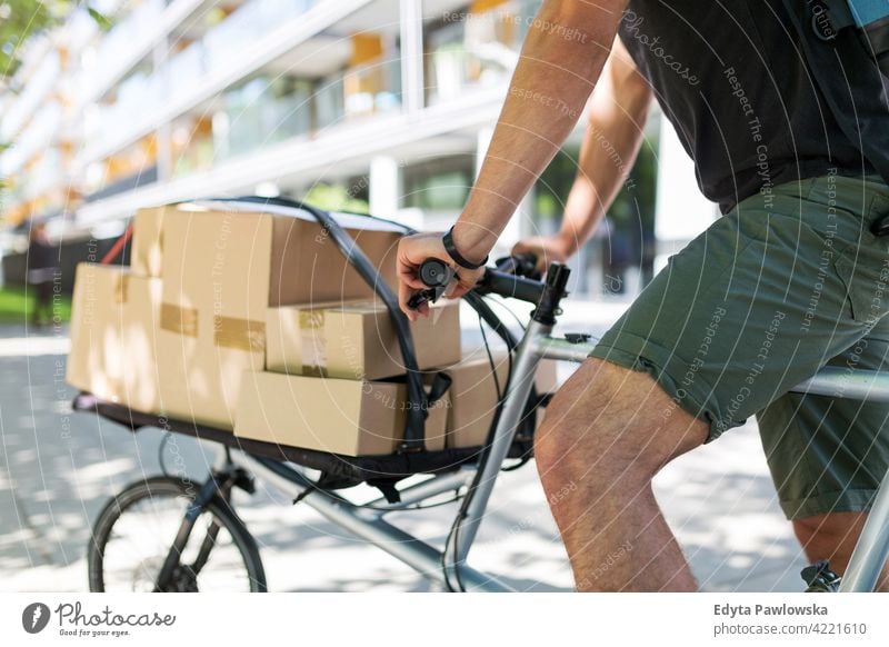 Fahrradkurier bei einer Lieferung Menschen junger Erwachsener Mann männlich Lächeln Glück blauer Kragen Kurier Meldereiter Auslieferer Versand liefernd Paket
