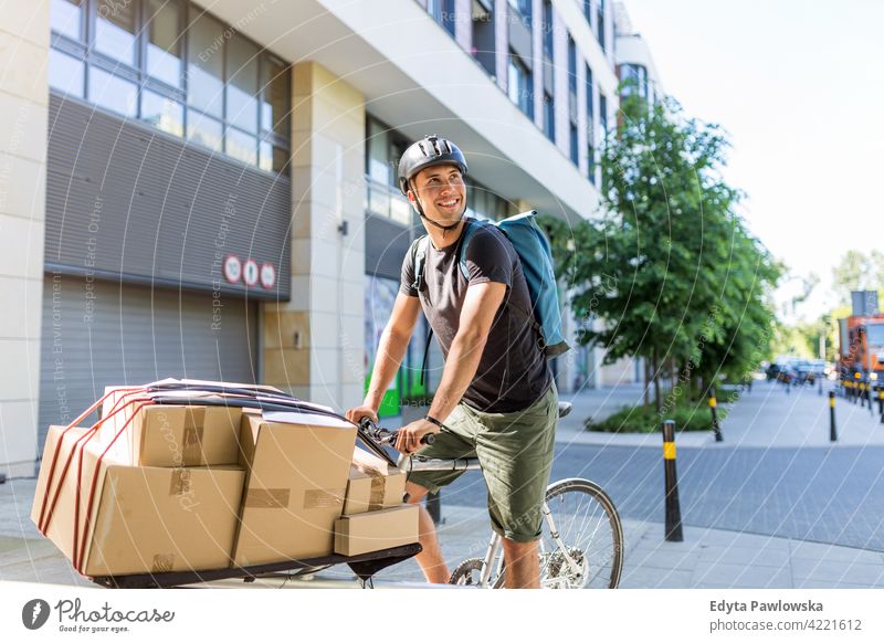 Fahrradkurier, der eine Lieferung auf einem Lastenfahrrad macht Menschen junger Erwachsener Mann männlich Lächeln Glück blauer Kragen Kurier Meldereiter