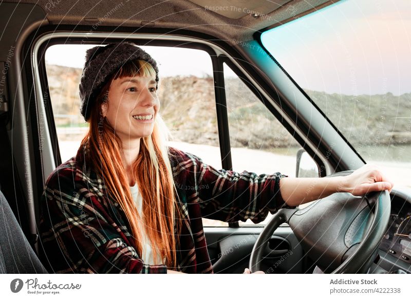 Fröhliche Frau in Van in den Bergen sitzend Reisender Kleintransporter Lastwagen Berge u. Gebirge Hipster reisen Ausflug Fahrer geparkt Fahrzeug Verkehr Lächeln