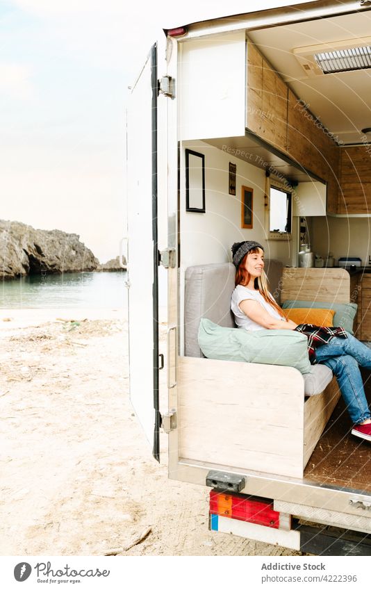 Zufriedene Frau entspannt sich auf dem Sofa im Van reisen Kleintransporter Reisender Lastwagen See Hipster Urlaub genießen sitzen ruhen Feiertag Sommer Ausflug