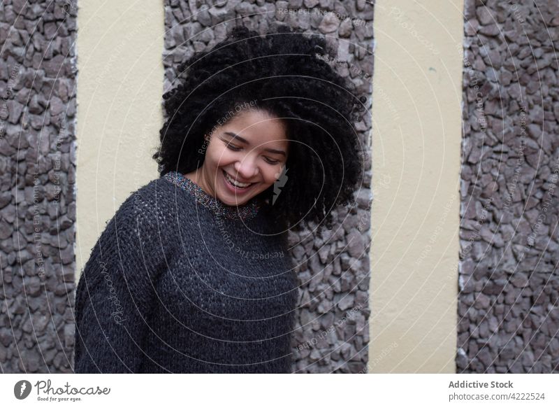 Glückliche ethnische Frau mit lockigem Haar in der Stadt Afro-Look Frisur Lächeln charmant krause Haare Vorschein Schönheit natürlich heiter Großstadt jung froh