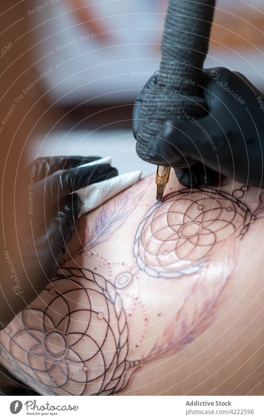 Tätowierer beim Anbringen einer Tätowierung auf der Hüfte einer anonymen Frau in einem Geschäft zeichnen Tattoo Klient Kunst präzise Fokus Frauen Tattoo-Shop